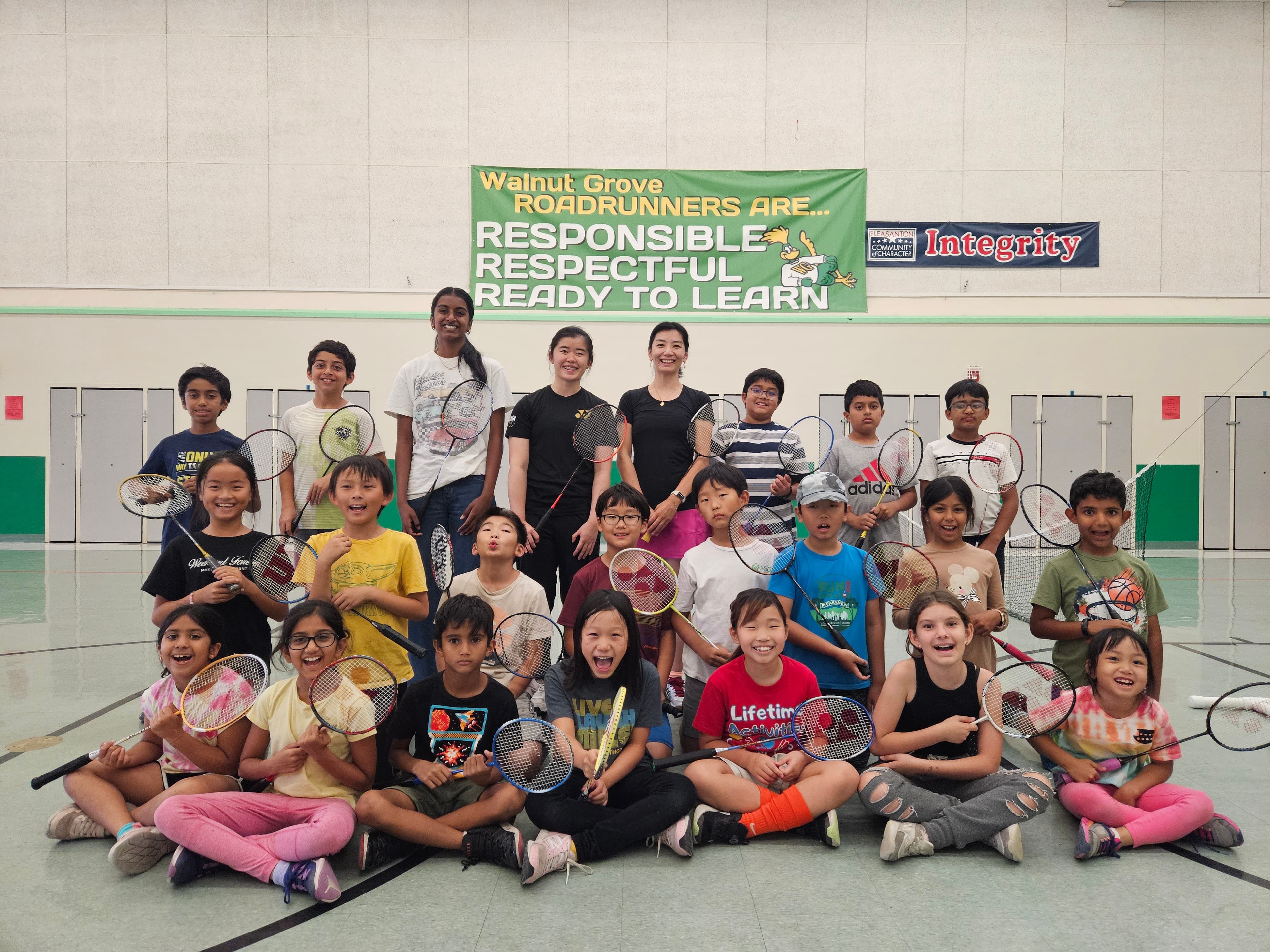 The full MindSpark Bay group of students and coaches holding badminton rackets at Walnut Grove Elementary